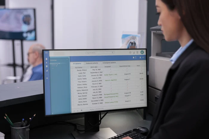 Asian receptionist checking patient consultation report on computer working in hospital waiting area - Why Medisoft Freezes and How to Fix It - Computer Mate - Medisoft Software