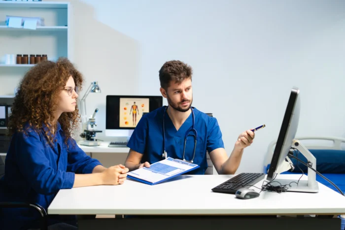 Male doctor explains health scan results to female patient using a computer screen. Concept - Medisoft Running Slow? Here’s How to Fix It Fast - Computer Mate - Medical Software