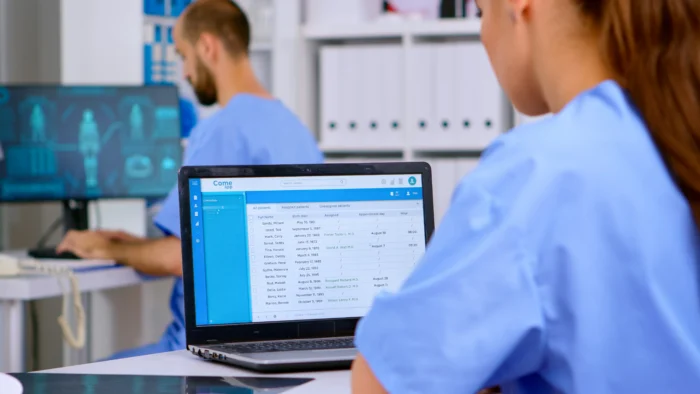 Professional doctor assistant checking medical records on laptop - Computer Mate - Medical Software